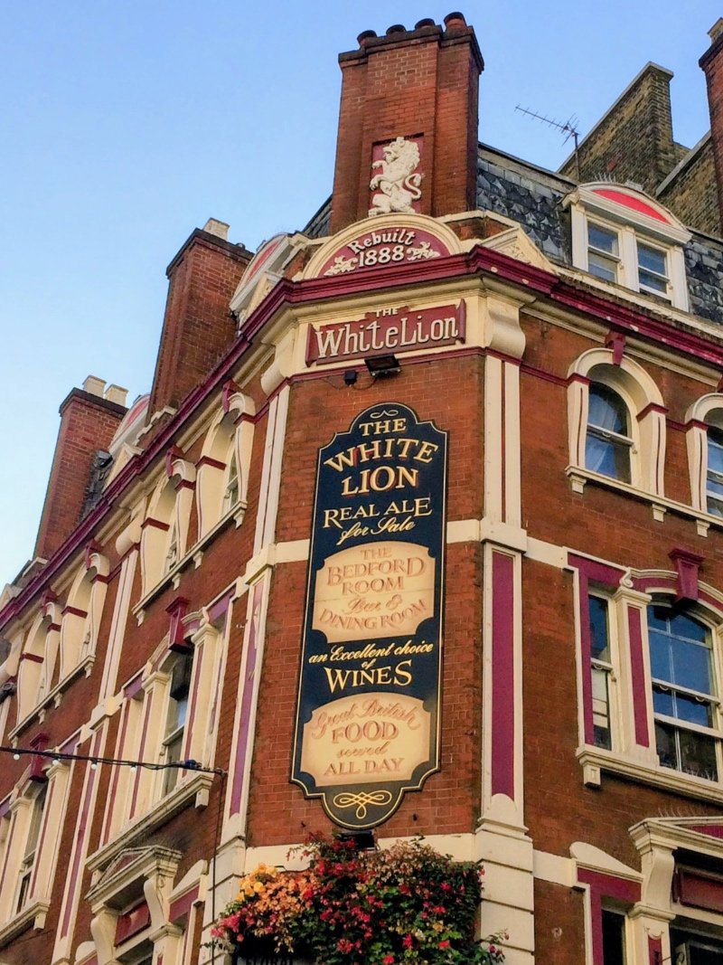 Classic style hand-painted sign using script and roman lettering at The White Lion in England